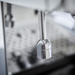 Close-up of a stainless steel coffee machine component.