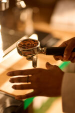 Barista holding portafilter with ground coffee.