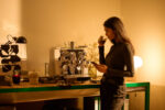 Woman enjoying coffee near an espresso machine.