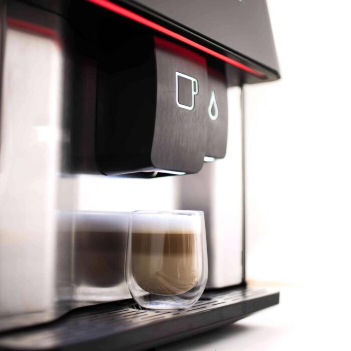 Coffee machine dispensing a latte into a glass.