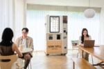 Two people in a café with a vending machine.