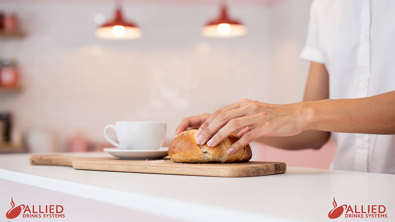 Barista serving bagel and coffee in café